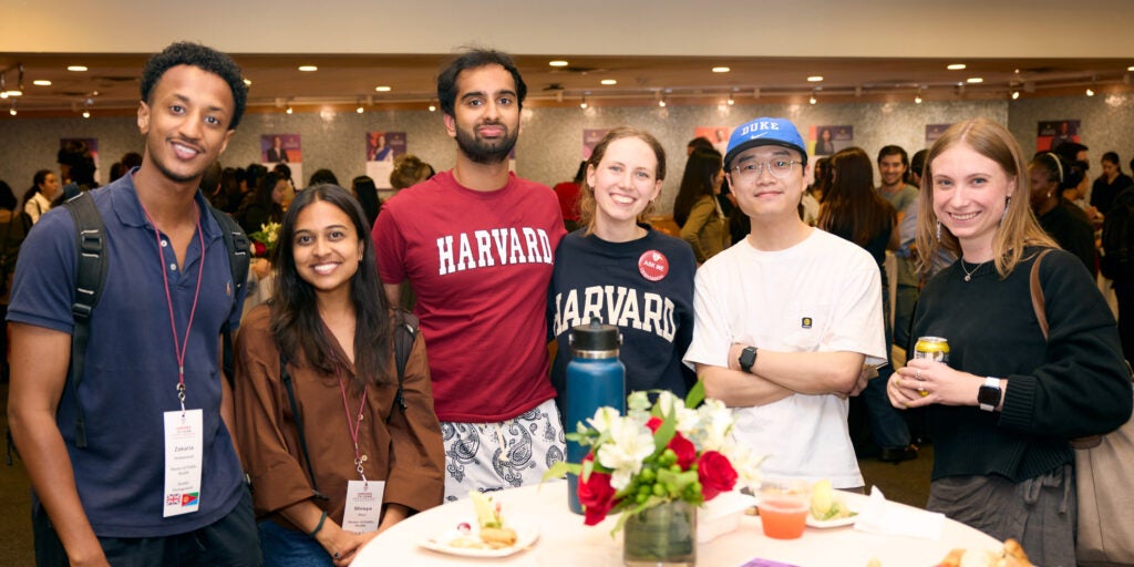 Five diverse students pose for a photo in front of a round table at an orientation reception.
