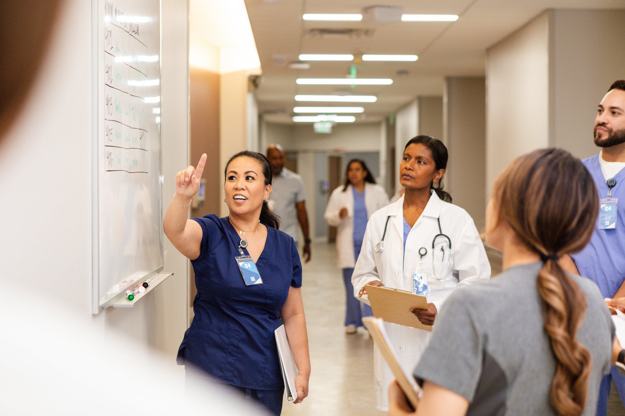 Negotiation skills for nurse leaders in practice as a nurse leads a discussion with her health care team at a whiteboard.