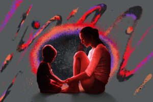 A child and mother sitting on the ground, facing each other, holding hands.