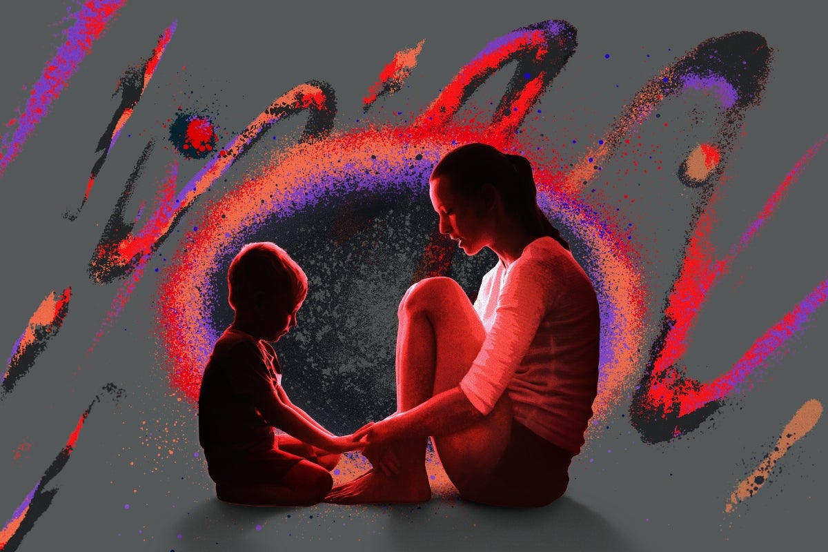 A child and mother sitting on the ground, facing each other, holding hands.