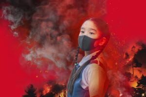 A girl wearing a mask superimposed on a smoky background with a fire and with trees.