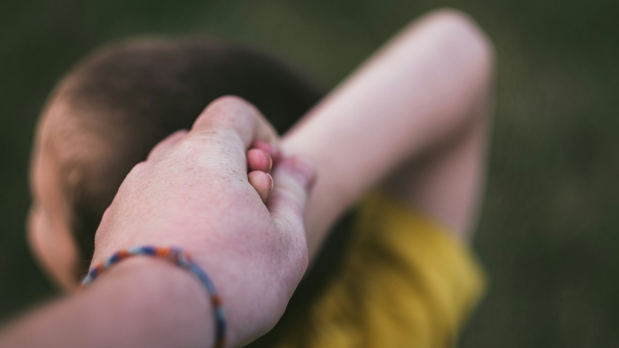 Child holding hands with adult, rear view. Photo: Andrew Seaman / Unsplash