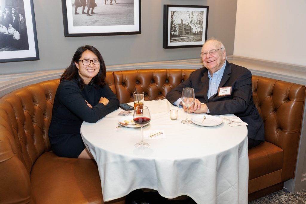 A man and woman seated in an upholstered leather booth. 