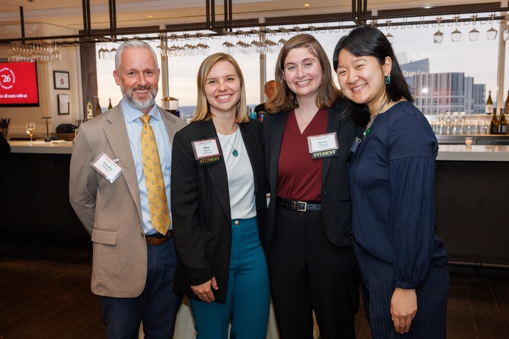 A group of four students and alumni pose together. 