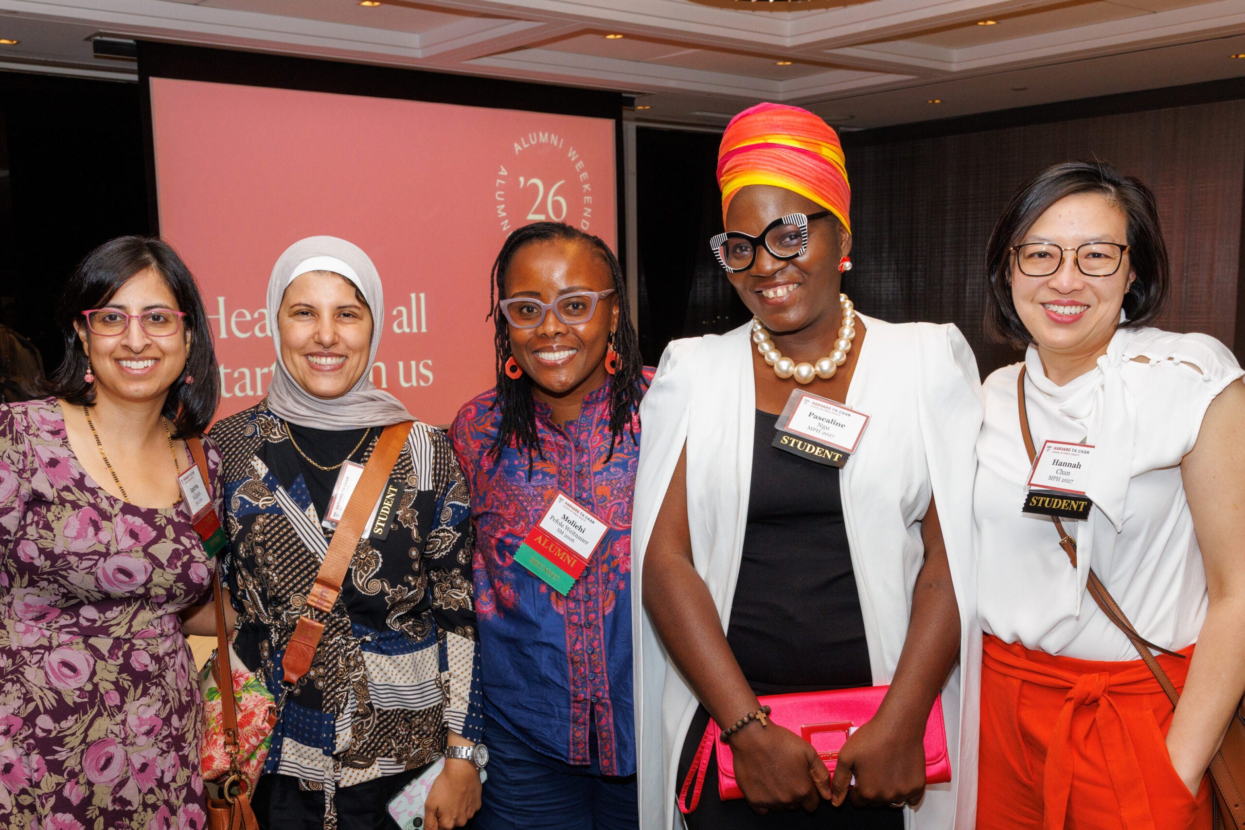 A group of five students and alumnae in colorful attire. 