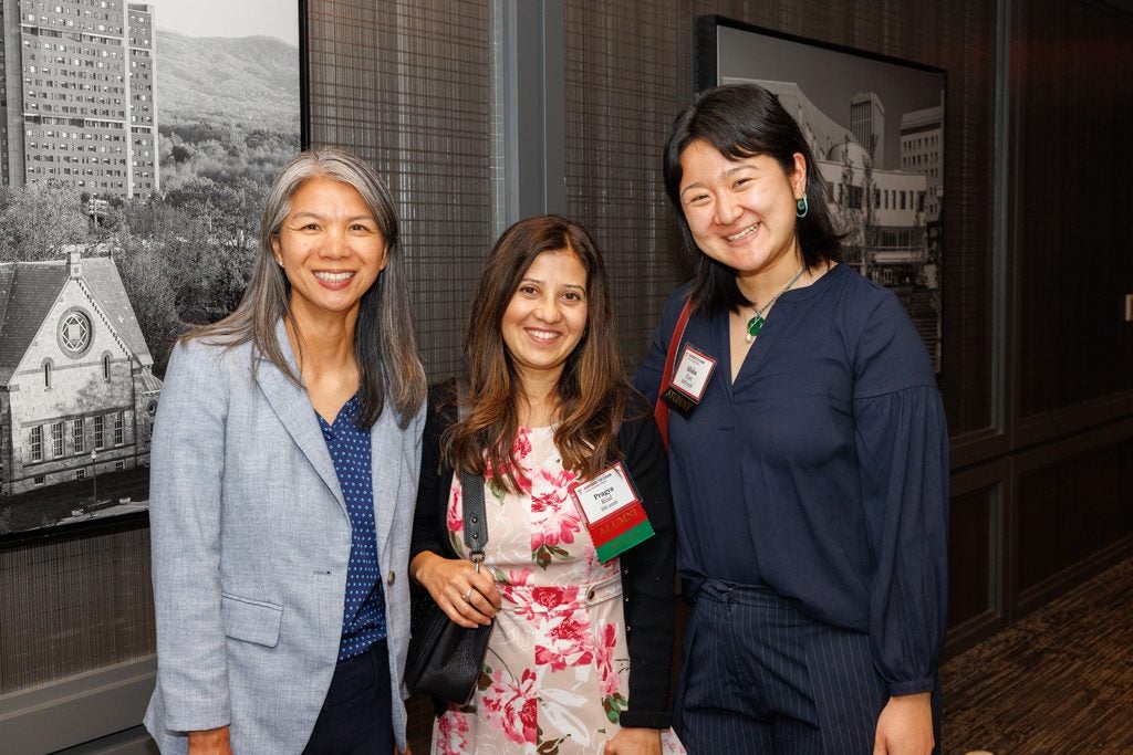 Two alumnae pose with a student. 