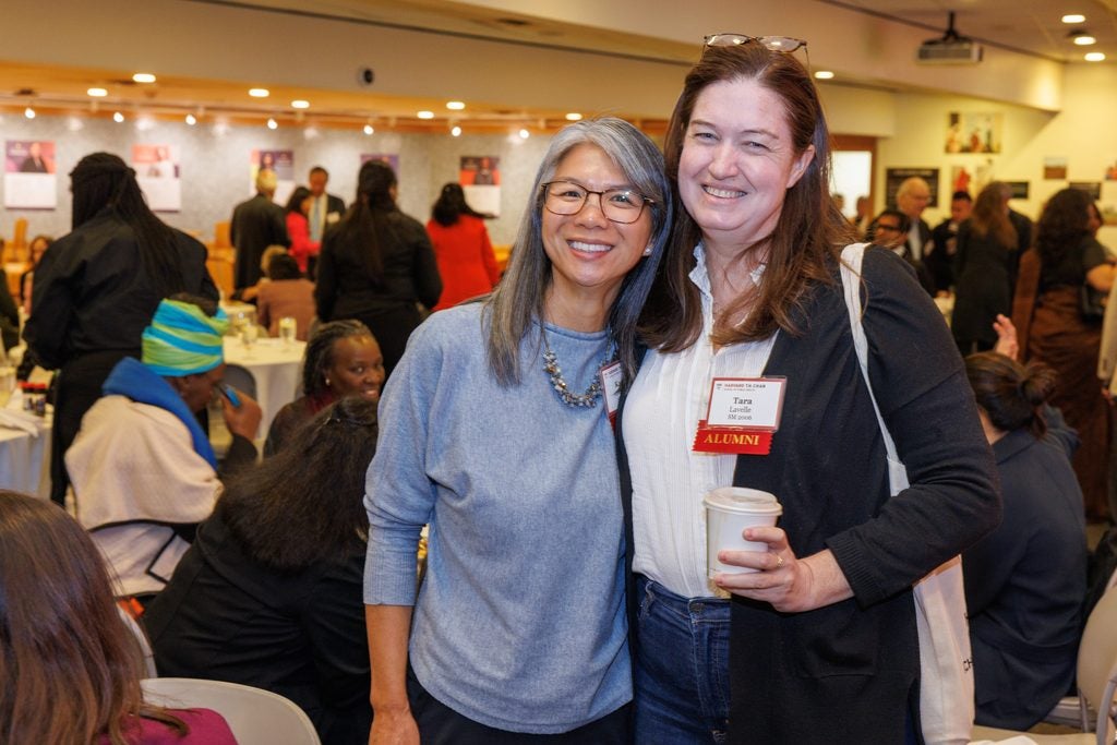 Two alumnae pose together among the luncheon tables. 