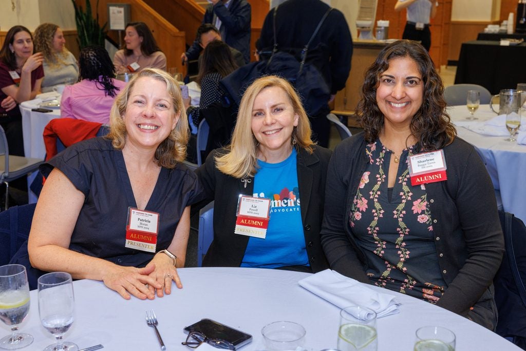 Three alumnae, including two presenters, pose sitting at a table. 