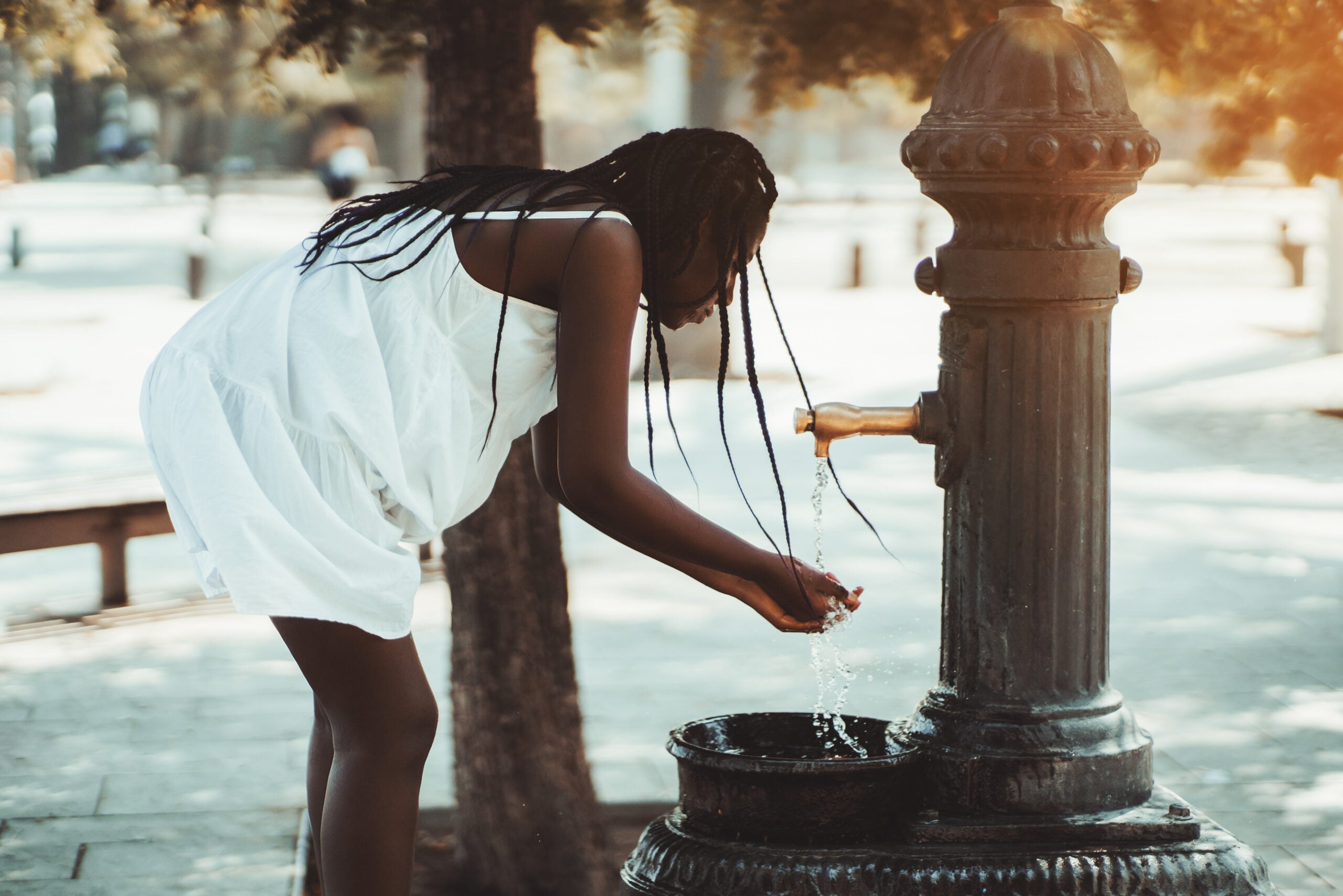 woman drinking from a water fountain on a hot day