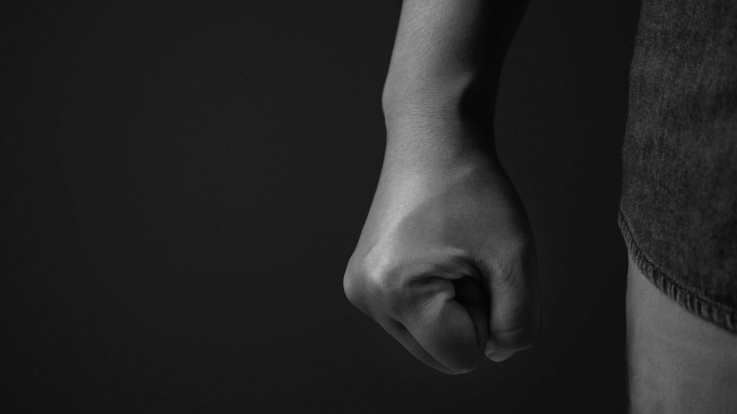 black & white close up photo of a clenched fist down by someone's side