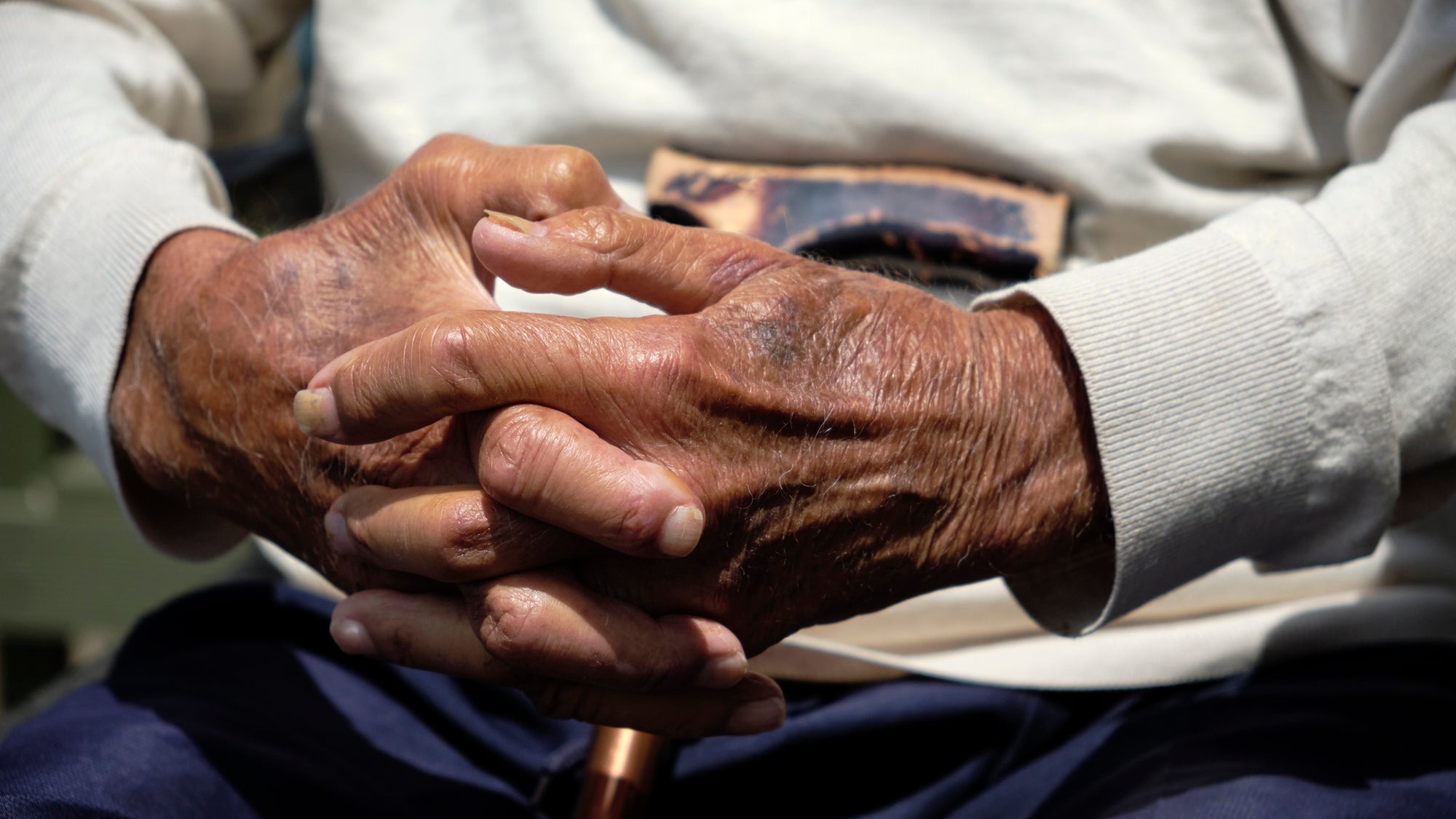 Close up of a man's hands holding a cane