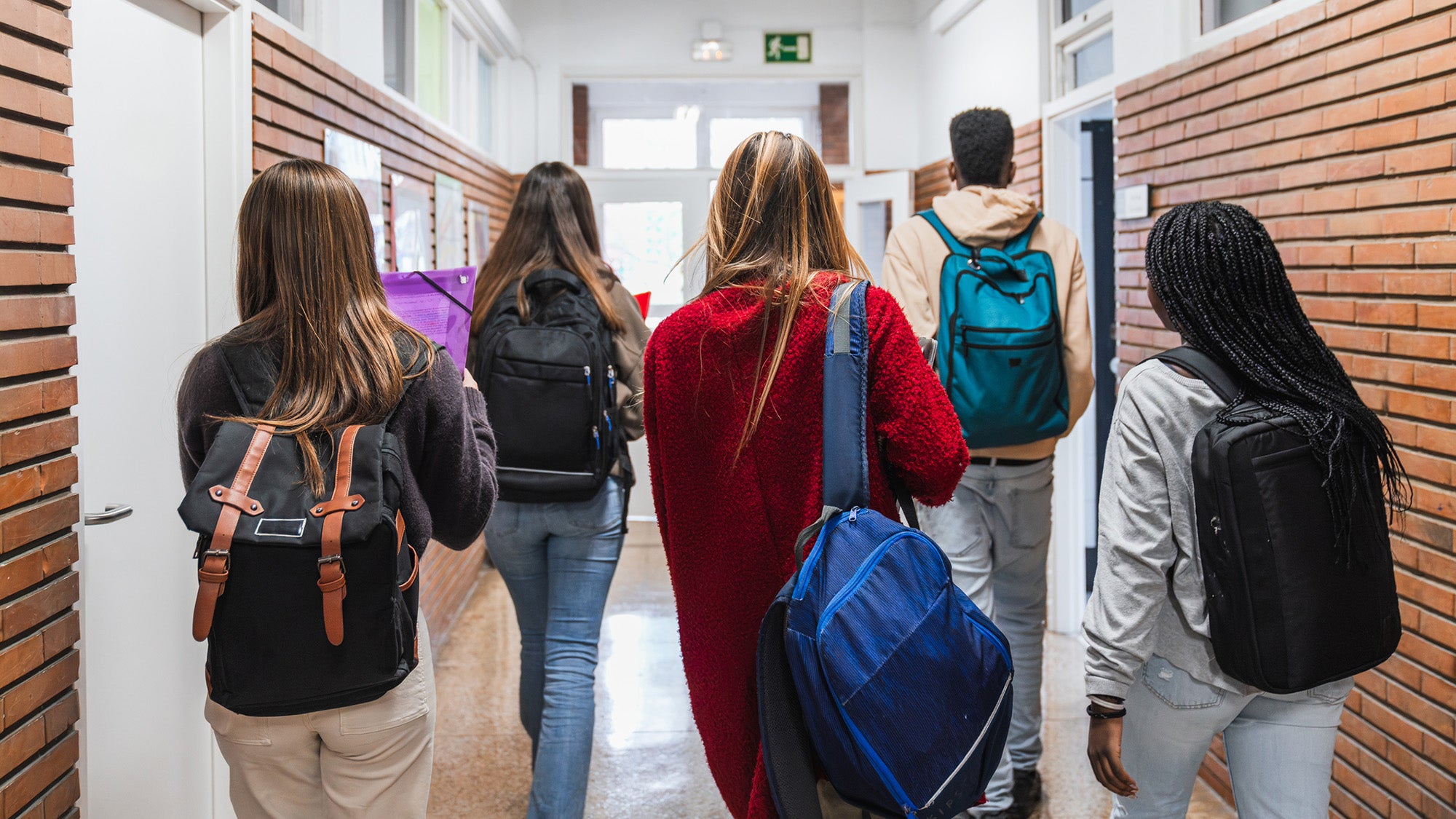High school students walking in a hallway, from rear