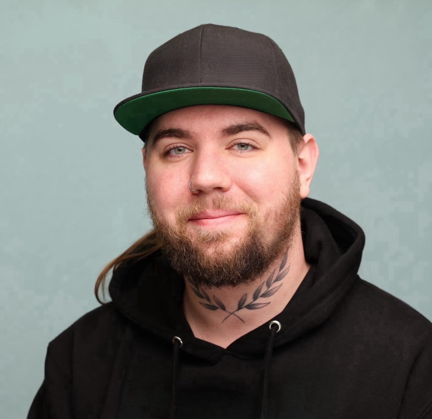 Kody Green wearing a black hoodie and grey hat with a green brim.