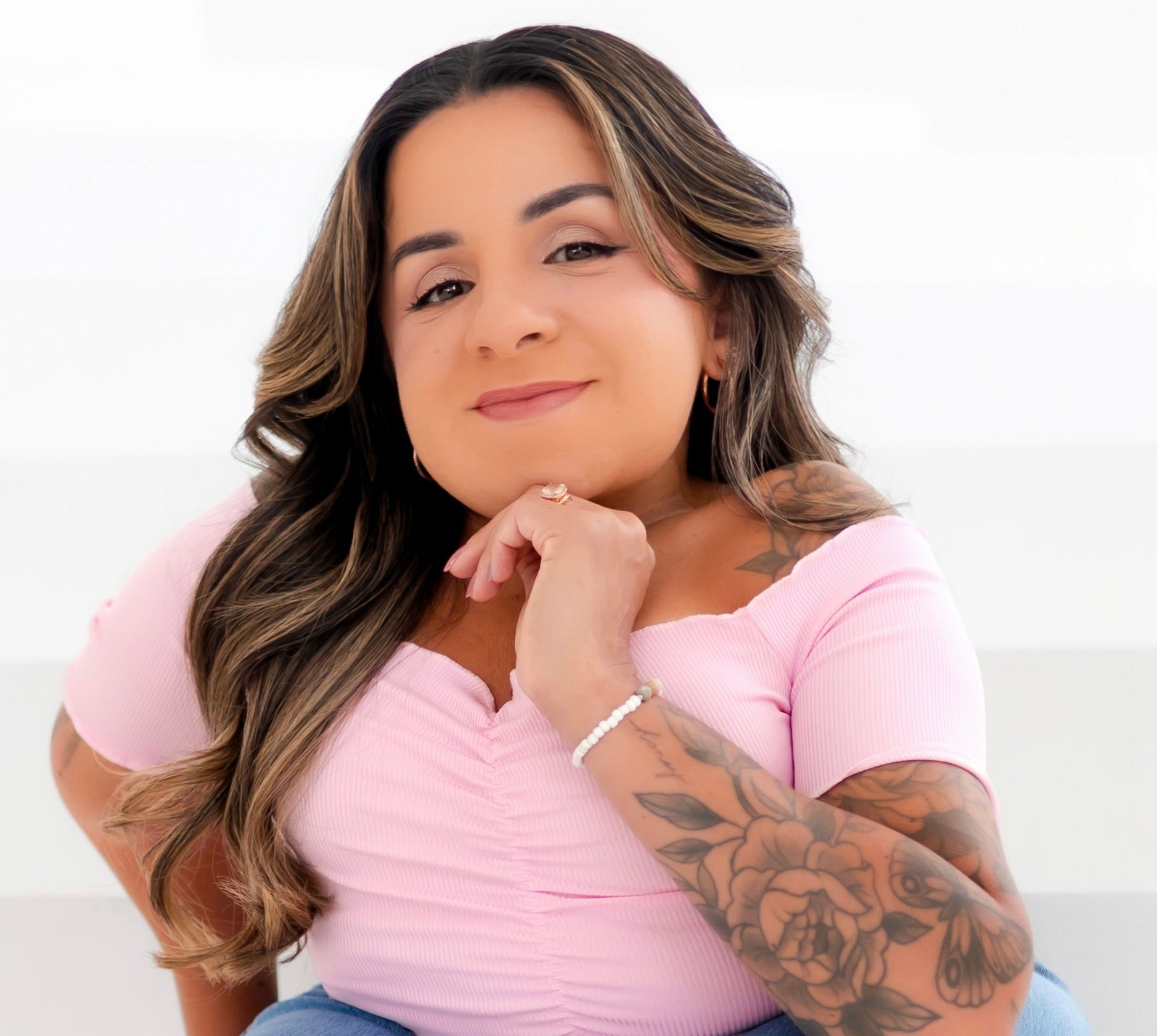 Steffi G in a pink tshirt and blue jeans against a white backdrop.