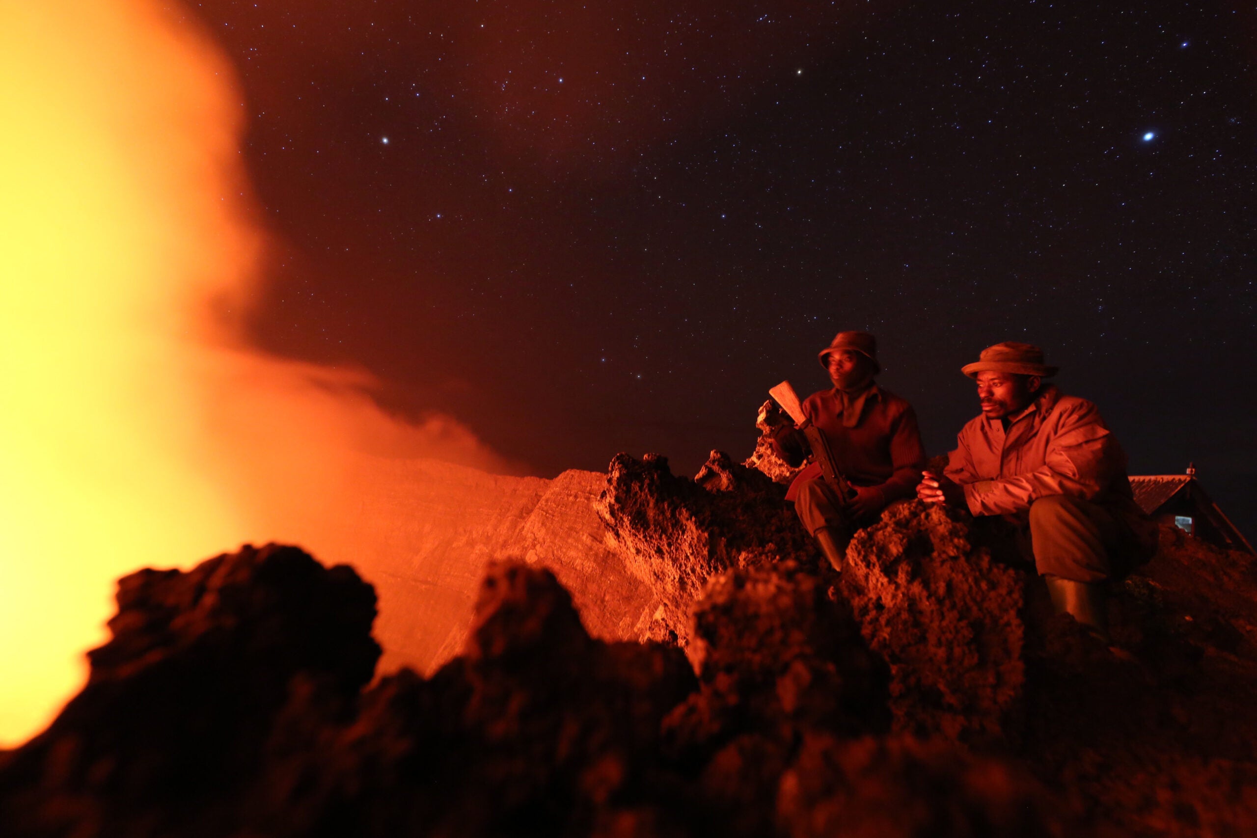 Two guards of the Virunga National Park contemplate the lava of Nyiragongo crater, which rises to 3470 meters.