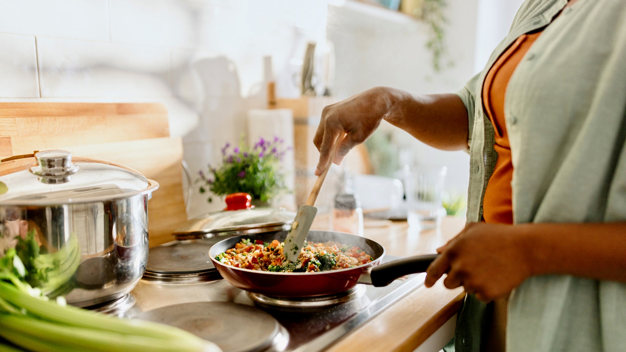 A woman cooks quinoa vegetable dish
